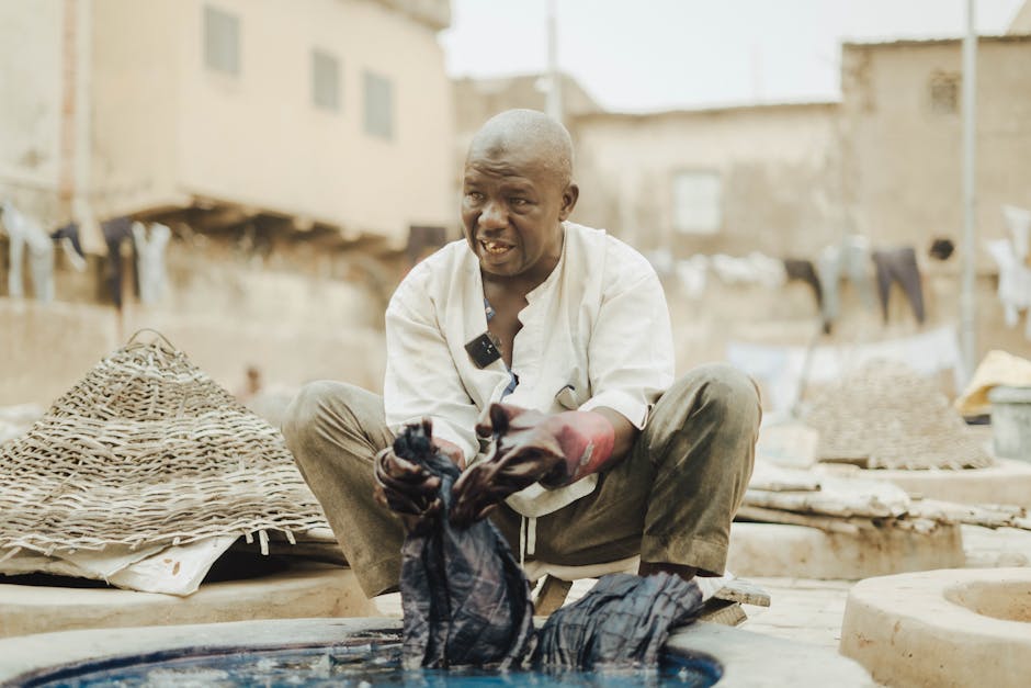Man involved in traditional fabric dyeing process in an open-air workshop, showcasing local craftsmanship.