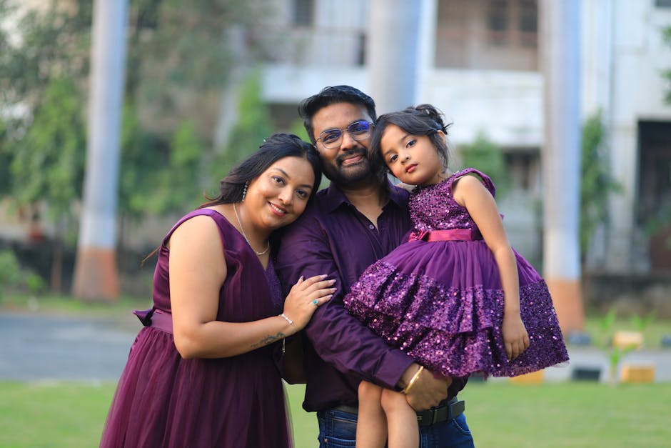 A cheerful family of three enjoying a sunny day outdoors, dressed in elegant matching outfits.