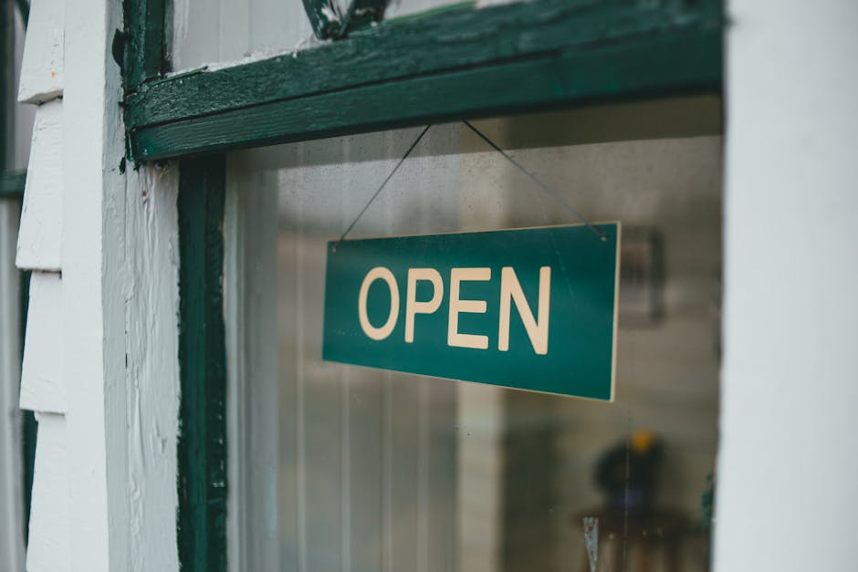 Close-up of green open sign hanging on window, inviting customers.