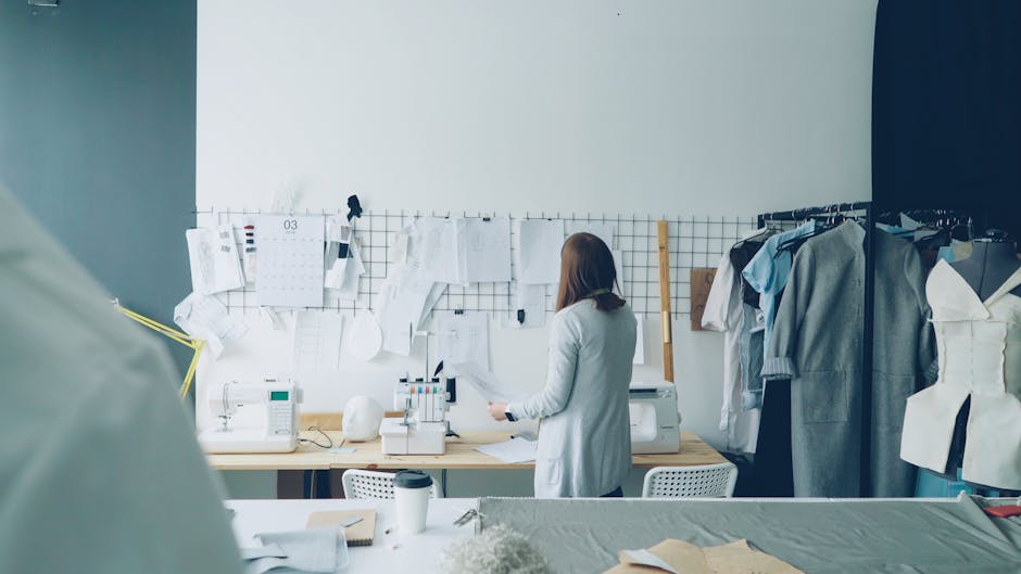 Fashion designer working in a modern studio with sewing machines and clothing designs.